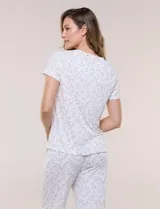 Conjunto pijama de remera de manga corta y pantalón capri blanco con delicado estampado floral en tonos rosados y verdes, confeccionado en tejido acanalado fino con escote redondo y detalle de gota con botón.