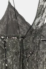 Top de encaje color gris oscuro, con escote en pico, tirantes finos y detalle de pañuelo incorporado al cuello. Presenta aplicaciones de abalorios y lentejuelas a contraste.