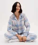 Pijama de dos piezas estilo americano confeccionado en franela. La blusa cuenta con cuello solapa, manga larga, cierre frontal con botones y un bolsillo en el pecho. El pantalón posee cintura elástica. Ambas prendas presentan un estampado de cuadros en tonos azul y blanco.