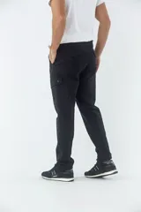 Pantalón cargo de corte slim, color negro, con bolsillos laterales con solapa y botones metálicos. Cuenta con cierre frontal, botón en la cintura y pasacintos.