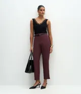 Pantalón carrot sastrero de corte recto y cintura alta, confeccionado en crepé. Presenta trabillas en la cintura, cierre tradicional y bolsillos traseros decorativos. Incluye un cinturón fino de material sintético.