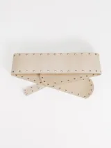 Faja ancha de cuero color beige, decorada con tachas metálicas en los bordes y hebilla circular metálica.
