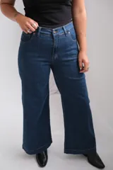 Jean de tiro alto y corte wide leg, confeccionado en denim azul oscuro con costuras en contraste.