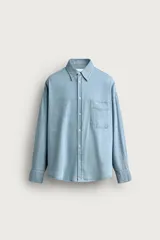 Camisa regular fit de denim de algodón con efecto lavado, cuello solapa y manga larga con puño abotonado. Tiene un bolsillo de parche en el pecho con detalle bordado a contraste y cierre frontal con botonadura.
