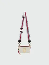 Cartera bandolera Marc Jacobs modelo The Snapshot, color crema con detalles en rojo y herrajes dorados. Presenta doble compartimento con cierre y correa de tela con logo de la marca.