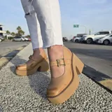 Zapatos tipo guillermina de cuero color tostado con efecto desgastado, plataforma alta y taco ancho. Presentan tira en el empeine con hebilla metálica rectangular y costuras visibles en el borde de la suela.