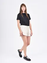 Short negro de tela de buzo, con cintura elástica ajustable con cordón y bolsillos laterales. El ruedo tiene una abertura lateral.