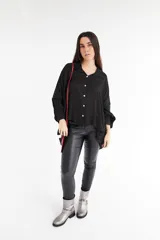 Camisa negra de satén con cuello clásico, corte holgado y cierre frontal con botones blancos.