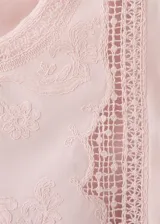 Top de algodón color rosado, con detalles bordados, cuello redondo, mangas cortas y terminaciones festoneadas.