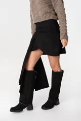 Falda de cuero marrón con diseño asimétrico, presenta un detalle de lazo frontal drapeado que crea una caída lateral más larga.