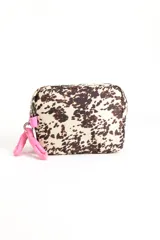 Necessaire rectangular con estampado animal print tipo vaca en tonos marrones y crudo, cierre superior y tiradores de cordón rosa.