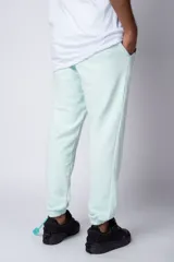 Pantalón jogger de corte oversize confeccionado en tela rústica color verde agua claro. Presenta una estampa gráfica localizada en el muslo izquierdo con diseño de óvalos y estrellas.
