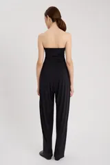Enterito negro strapless de tejido ultra elástico, con silueta ajustada en la parte superior y corte holgado en la parte inferior, con efecto curvo que se cierra en el tobillo.