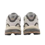 Championes urbanos New Balance modelo 2010, con diseño de paneles en tonos gris, beige y crema. Presentan una combinación de malla técnica y superposiciones de gamuza, con el logo N característico en el lateral y una entresuela robusta con detalles en color bronce.