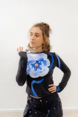 Remera crop de algodón elastizada negra con estampado de una flor azul.