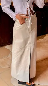 Falda larga color crema de cuero con tajo frontal y bolsillos laterales.