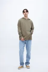 Canguro verde oliva de felpa liviana teñido en prenda, con capucha, bolsillo tipo canguro y puños acanalados. Estampa con la leyenda "UNFRM-STATE" en el pecho y detalle de estampa en la manga. Corte recto.