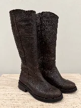 Botas altas de cuero marrón oscuro texturado, con suela plana y baja, puntera redondeada y cierre lateral interno.