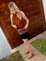 Top halter confeccionado en cuero color camel, con diseño sin mangas, espalda descubierta y ajuste mediante tiras.