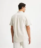 Camisa de corte comfort confeccionada en mezcla de lino y algodón, con cuello inglés, cierre frontal de botones, manga corta con dobladillo y un bolsillo frontal aplicado.