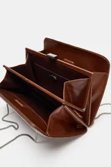 Bolso de hombro de piel marrón oscuro, formato rígido y rectangular, con detalle de pespuntes que crean un patrón de cuadrados. Posee triple compartimento y doble asa de hombro en cadena metálica dorada.