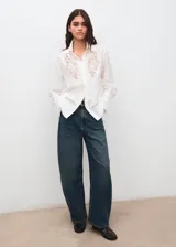 Camisa blanca de manga larga con detalles bordados calados en el frente y puños anchos.