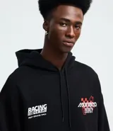 Buzo con capucha y bolsillo canguro, confeccionado en algodón con felpa. Presenta un diseño estampado con temática de carreras en el frente y la espalda, con corte relajado y cordón ajustable en la capucha.