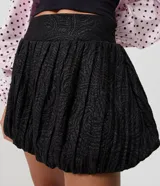 Minifalda negra de jacquard con tiro alto, cintura estructurada y corte baloné voluminoso.