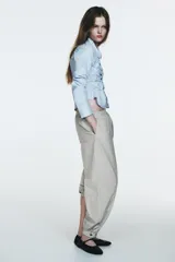 Pantalón bombacho de tiro medio con cintura elástica, confeccionado en tejido de nylon con estampado de cuadros pequeños en blanco y negro. El bajo es elástico con abertura y botón a presión.