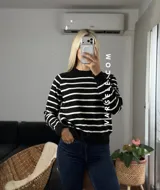 Sweater de punto con diseño de rayas horizontales negras sobre fondo blanco, cuello redondo y puños y ruedo acanalados.