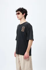 Remera negra de corte amplio con mangas cortas y cuello redondo. Presenta un pequeño estampado rectangular en el pecho y un estampado grande en la espalda con motivos japoneses.