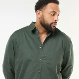Sobrecamisa de algodón en color verde oscuro, con cierre frontal de botones, cuello clásico y un bolsillo aplicado en el pecho.