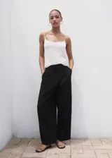 Pantalón wide leg de tiro medio color negro, con diseño largo, bolsillos laterales, bolsillos de ribete posteriores y detalle de pinzas. Cuenta con cierre oculto de botón, gancho y cremallera, e incluye forro interior.