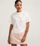 Blusa boxy de mangas cortas y cuello redondo, confeccionada en algodón, con flores de tejido aplicadas en el hombro y la sisa.