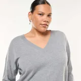 Sweater de punto fino color gris, con escote en V y mangas largas de corte holgado.