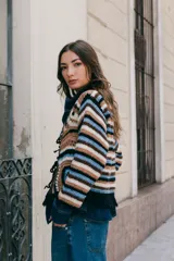 Saco tejido en crochet con diseño de rayas horizontales en mangas y espalda. Presenta un cierre frontal con lazos de crochet en el escote en V y detalle de flecos en el ruedo.