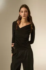 Top de manga larga color negro, con cuello en V y diseño drapeado en el frente. Confeccionado en tejido ajustado al cuerpo.