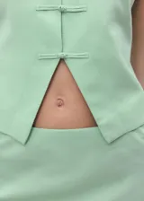 Chaleco verde menta sin mangas, con cuello redondo y cierre frontal con nudos y presillas de tela.