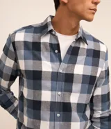 Camisa de franela para hombre, modelo comfort, con estampado de cuadros en tonos azules, blancos y negros, cuello camisero, manga larga y cierre frontal de botones.