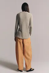 Chaqueta de punto color beige con escote en V, manga larga y cierre frontal con botones dorados.