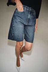 Bermuda de denim color bordó, de tiro medio y corte relaxed, con diseño de cinco bolsillos, trabillas para cinto y bajo desflecado.