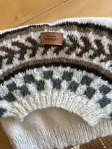 Sweater tejido a mano en lana mohair premium, color celeste con diseño geométrico en blanco, rosa y marrón.