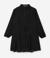 Vestido corto tipo chemise de poliéster con estampado de lunares, cuello camisero con botones frontales, mangas largas con puños elásticos y lazo ajustable en la cintura.