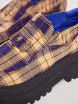 Mocasines con plataforma de goma negra, confeccionados en lona con estampa a cuadros en tonos violeta, amarillo y beige, y detalle de elásticos laterales ocultos.
