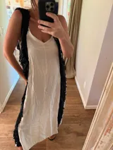 Vestido largo de estilo lencero color crema, con puntillas negras aplicadas verticalmente en el frente y la espalda.