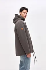 Campera tipo parka de gabardina color beige, con capucha ajustable, cierre frontal y bolsillos laterales con solapa. Presenta un diseño clásico con interior capitoneado.