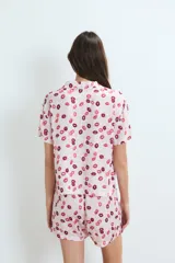 Pijama de dos piezas compuesto por una camisa de manga corta con botones frontales y un short, ambos con estampado de labios en tonos rosados y rojos.