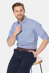Camisa de manga larga de algodón, color celeste con sutil diseño a cuadros, corte slim fit, cuello camisero, bolsillo ojal en el pecho con logo bordado y mangas convertibles con presilla.