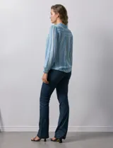 Camisa de gasa celeste con estampado de rayas verticales en tonos azules, rosas y verdes. Tiene cuello con solapa, escote en V, abertura central con botones, bolsillo aplicado en el pecho y terminación anudada en la parte delantera.