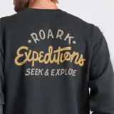 Buzo de cuello redondo color negro, con estampado pequeño en el pecho izquierdo que incluye el logo de la marca y la frase 'Roark Expeditions'. Presenta puños y ruedo acanalados.